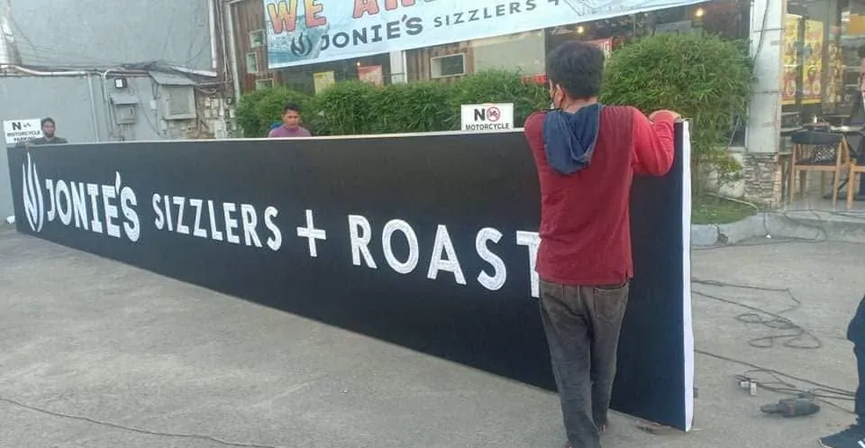 MCAV crew installing a Jonie's Sizzlers + Roast sign
